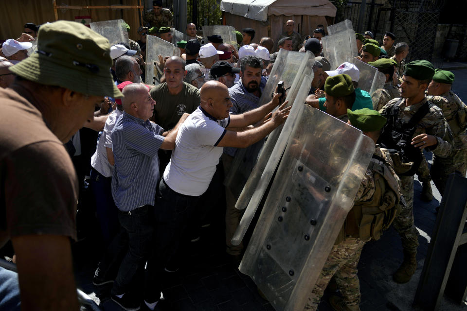 Soldiers scuffle with retired army members as they try to enter to the parliament building while the legislature was in session discussing the 2022 budget, during a protest in downtown Beirut, Lebanon, Monday, Sept. 26, 2022. The protesters demanded an increase in their monthly retirement pay, decimated during the economic meltdown. (AP Photo/Bilal Hussein)