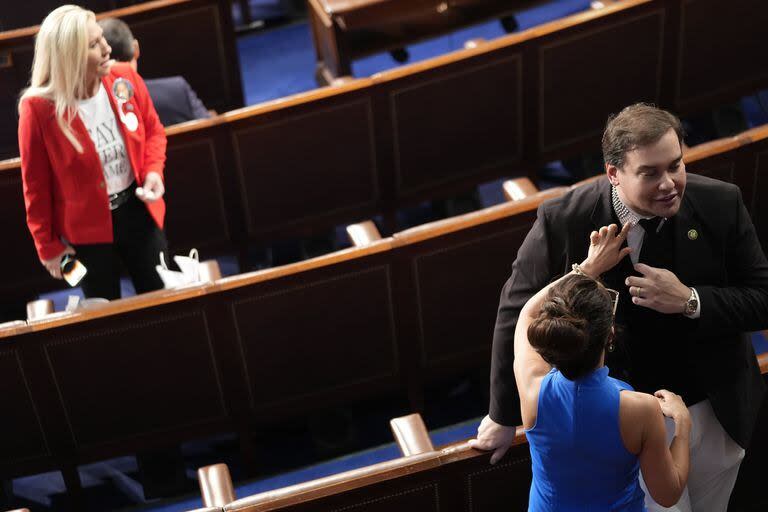 La representante Lauren Boebert, republicana por Colorado, mira el cuello de la camisa del ex representante George Santos; detrás está Marjorie Taylor Greene