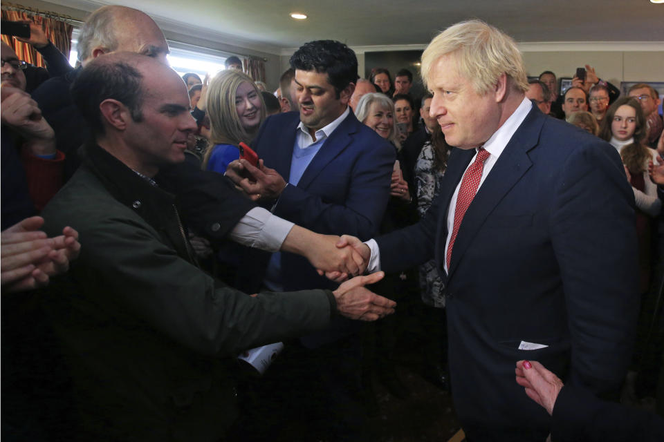 Britain's Prime Minister Boris Johnson shakes hands with supporters on a visit to meet newly elected Conservative party MP for Sedgefield, Paul Howell at Sedgefield Cricket Club in County Durham, north east England, Saturday Dec. 14, 2019, following his Conservative party's general election victory. Johnson called on Britons to put years of bitter divisions over the country's EU membership behind them as he vowed to use his resounding election victory to finally deliver Brexit. (Lindsey Parnaby/Pool via AP)