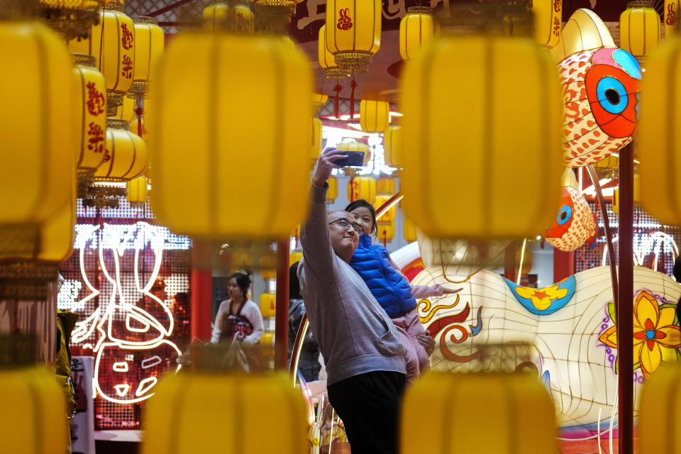 FILE - A man takes a selfie with a child with lantern decorations on display inside a shopping mall in Beijing on Feb. 5, 2023. The Lantern Festival, the end of the Lunar New Year holiday period, falls on Sunday. (AP Photo/Andy Wong, File)