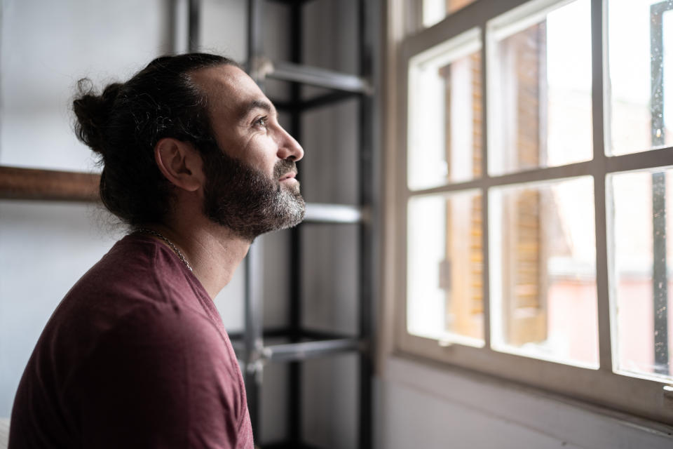 Man looking through the window at home. 