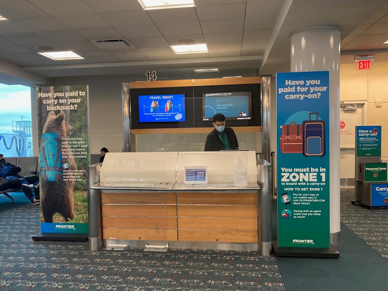 A gate agent is seen at a Frontier Airlines counter at Orlando International Airport.