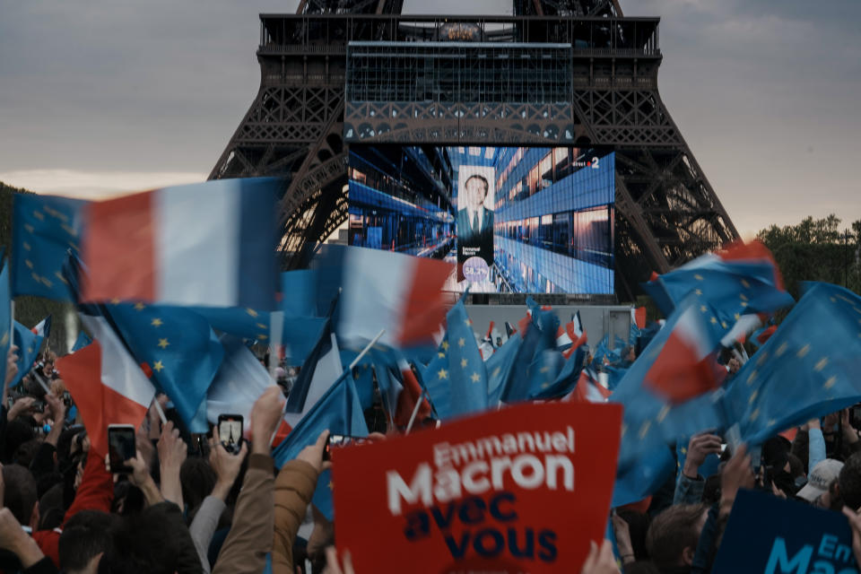 Supporters of French President Emmanuel Macron react as the first election projections are shown on a screen in front of the Eiffel Tower in Paris, France, Sunday, April 24, 2022. French polling agencies are projecting that centrist incumbent Emmanuel Macron will win France's presidential runoff Sunday, beating far right rival Marine Le Pen in a tight race that was clouded by the Ukraine war and saw a surge in support for extremist ideas. (AP Photo/Thibault Camus)