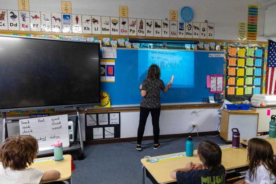 Betsi LaMoure resorts to using a document projector camera to teach a math lesson after a new smart board the school is testing, at left, fails to connect with the WiFi in her first grade classroom.