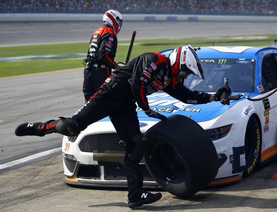 A crew member of Paul Menard trips over the tire as he runs back to the wall during a NASCAR Cup Series auto race at Talladega Superspeedway, Sunday, April 28, 2019, in Talladega, Ala. (AP Photo/Butch Dill)