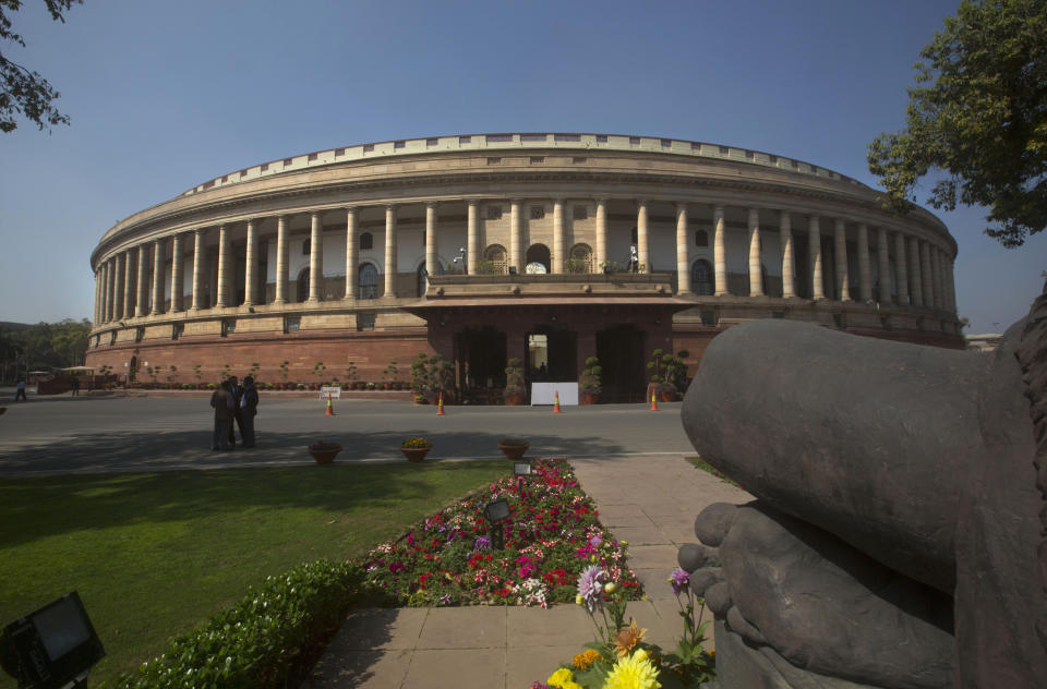 FILE- In this Feb. 23, 2016 file photo, the Indian parliament building is seen from behind a Mahatma Gandhi statue, right, in New Delhi, India. India's recent national election delivered a historic victory to Prime Minister Narendra Modi's Hindu nationalist party, but also exposed the influence of money, power and questionable morality on the world's largest democracy. (AP Photo/Manish Swarup, File)