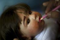 Mananya Boonmee, 49, works on the make-up of a "child angel" doll at her house in Nonthaburi, Thailand, January 26, 2016. REUTERS/Athit Perawongmetha