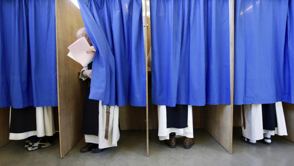 Monks from the Saint Sixtus Trappist Abbey cast their votes behind curtains at a polling station in Westvleteren, Belgium, Sunday, May 26, 2019. Belgium, which has one of the oldest compulsory voting systems, goes to the polls Sunday to vote on the regional, federal and European level. (AP Photo/Olivier Matthys)