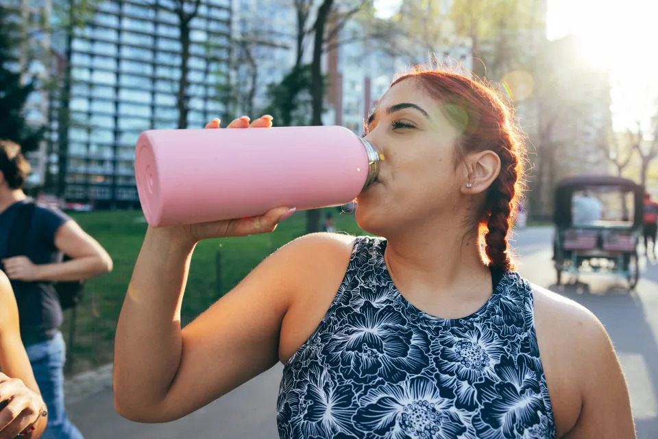 woman drinking out of a reusable water bottle