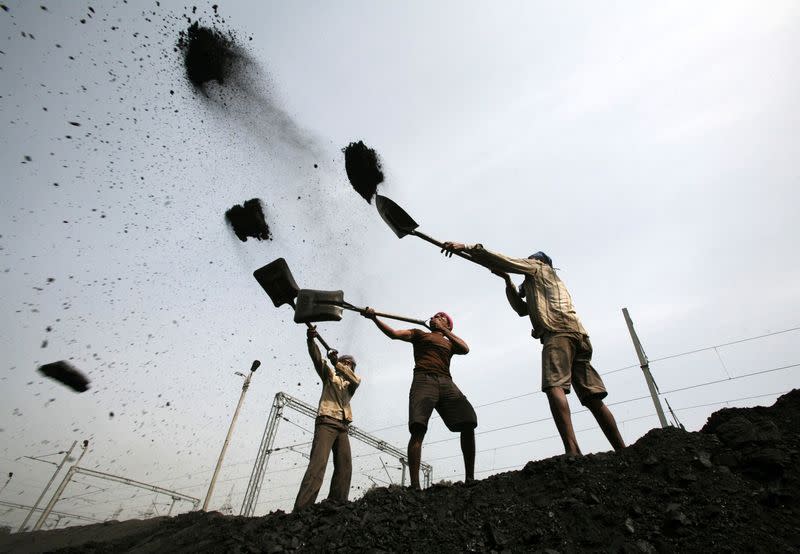 FILE PHOTO: Labourers load coal on trucks on the outskirts of Jammu