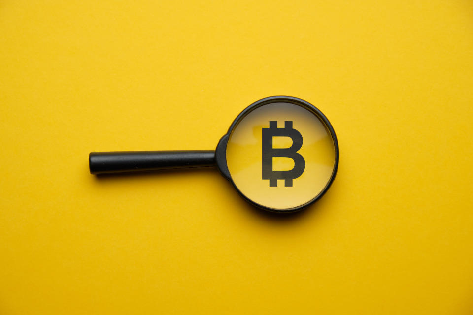Bitcoin cryptocurrency search concept with magnifying glass on a yellow background. Close up.