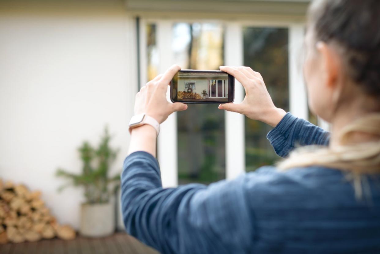 woman taking pictures of the house on a smartphone