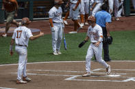 Texas Mitchell Daly, right, scores with Ivan Melendez, left, from a homer by Eric Kennedy in the second inning against Tennessee during a baseball game in the College World Series Tuesday, June 22, 2021, at TD Ameritrade Park in Omaha, Neb. (AP Photo/John Peterson)