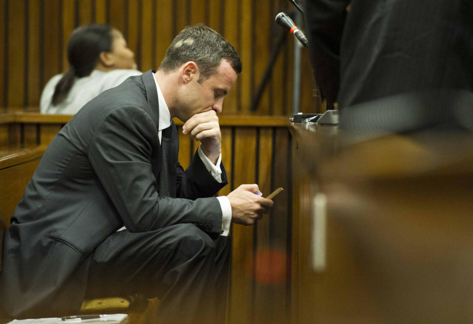 RETRANSMISSION TO CLARIFY THE SOURCE - Oscar Pistorius, checks his mobile phone in court on the fifth day of his trial at the high court in Pretoria, South Africa, Friday, March 7, 2014. Pistorius is charged with murder for the shooting death of his girlfriend, Reeva Steenkamp, on Valentines Day in 2013. (AP Photo/Theana Breugem, Pool)