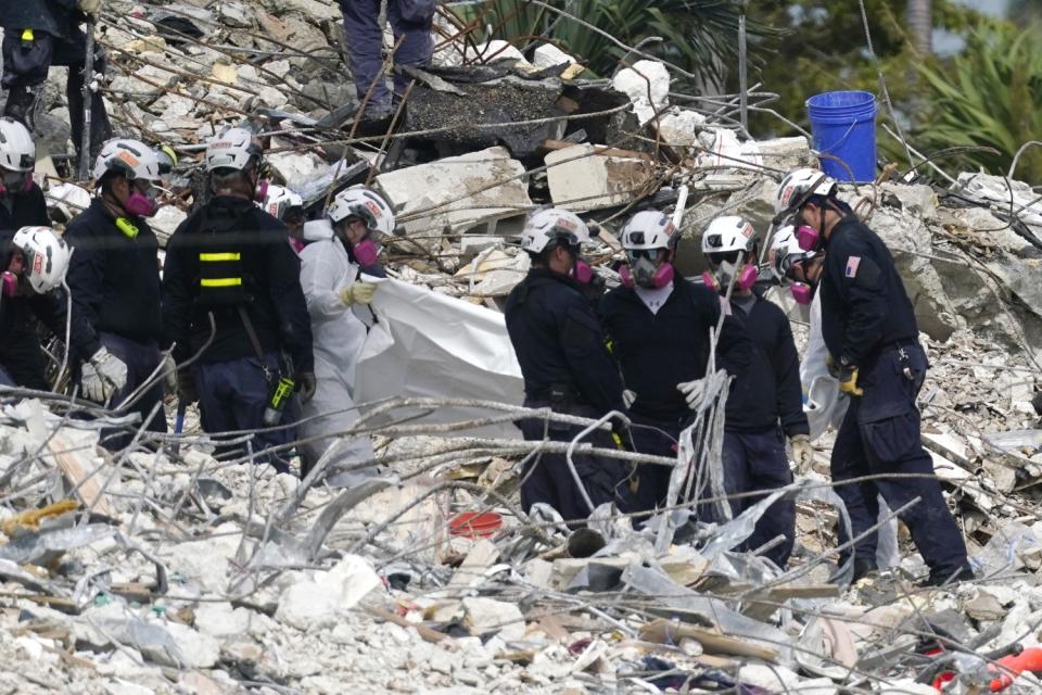 Rescue workers use a tarp for recovered remains at the site of the collapsed Champlain Towers South condo building