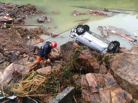 A rescue worker is seen next to an overturned car at the site of a landslide caused by heavy rains brought by Typhoon Megi, in Sucun Village, Lishui, Zhejiang province, China, September 29, 2016. REUTERS/Stringer