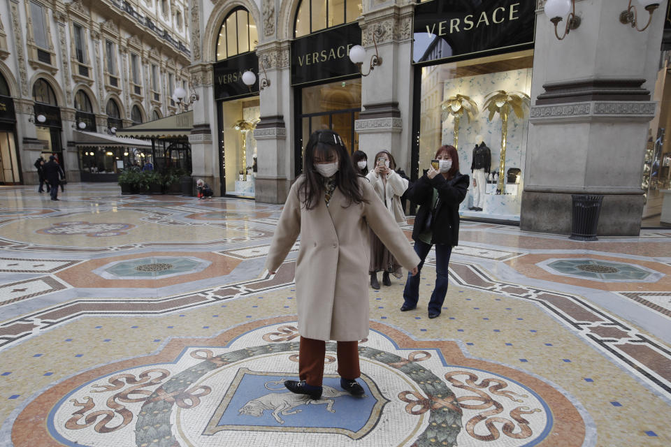 A tourist twirls around as she steps on a tiled floor mosaic depicting a bull, symbol of the city of Turin that was the first capital of the Kingdom of Italy, inside the four-story double arcade Galleria Vittorio Emanuele II, completed in 1867 and named after Italy's first king, in Milan, Italy, Thursday, Feb. 27, 2020. According to an old legend this will bring good luck and allow to return in the city. In Europe, an expanding cluster in northern Italy is eyed as a source for transmissions of the COVID-19 disease. (AP Photo/Luca Bruno)