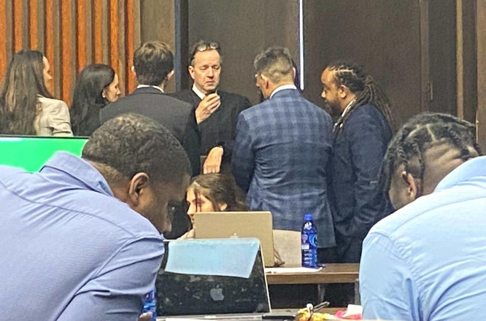 Terrance Upshaw, left in the foreground, murmurs to codefendant Rodderick Glanton as Judge Gil McBride holds a bench conference with attorneys in the background.