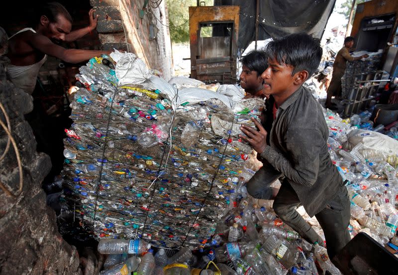 FILE PHOTO: Workers push a bundle of crushed plastic bottles at a recycling factory in Ahmedabad