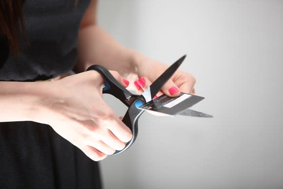 Person cutting up a credit card with scissors.