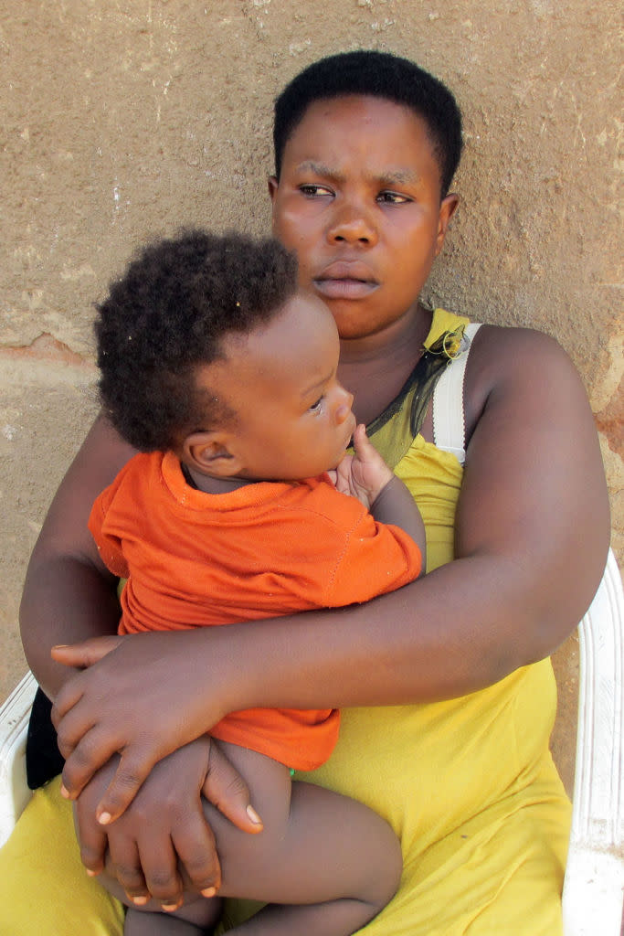The Ugandan woman Mariam Nabatanzi sits in front of the house with her youngest child, Sudaisha, in Kasawo, Uganda.