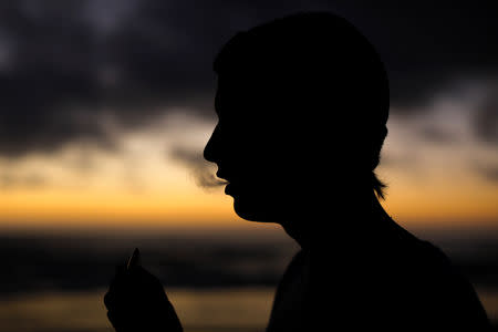 A young man smokes a Suorin Drop electronic cigarette in this picture illustration taken September 14, 2018. REUTERS/Mike Blake/Illustration