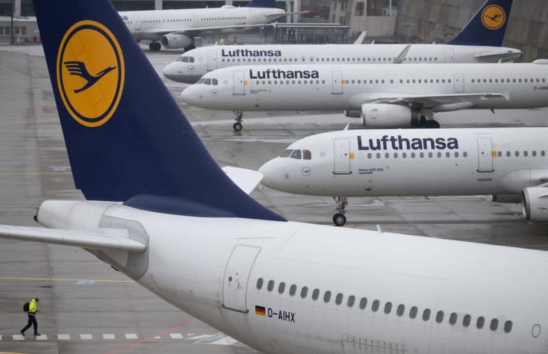 A man walks past Lufthansa passenger planes at Frankfurt Airport. Because of the weather conditions, the airport has scaled back its flight schedule. Boris Roessler/dpa