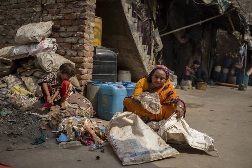 Sahra Bano sorts reusable items from the Bhalswa landfill on the outskirts of New Delhi, India, Wednesday, March 10, 2021. An estimated 20 million people around the world help keep cities clean by scavenging through landfills and dumps. Experts say these trash pickers, who sometimes toil alongside paid municipal sanitation workers, provide a vital service, yet they usually are not on a priority list for coronavirus vaccines. (AP Photo/Altaf Qadri)