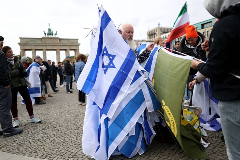 A man distributes Israeli flags to participants of a pro-Israel protest under the motto 'Together Against Hamas' Crimes Against Israelis and Palestinians,' marking the first anniversary of the October 7 attacks on Israel. Joerg Carstensen/dpa