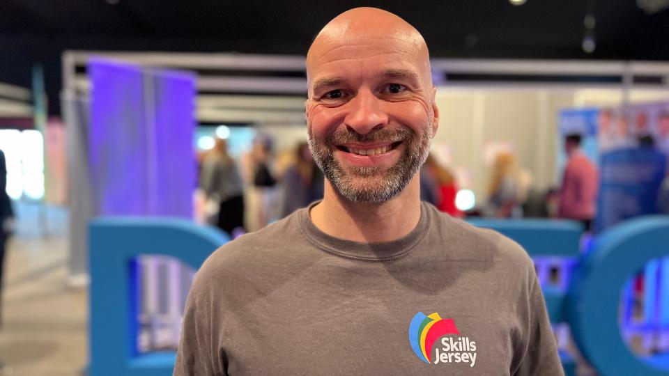 Stuart smiles at the camera as students check out employers' stalls in the background