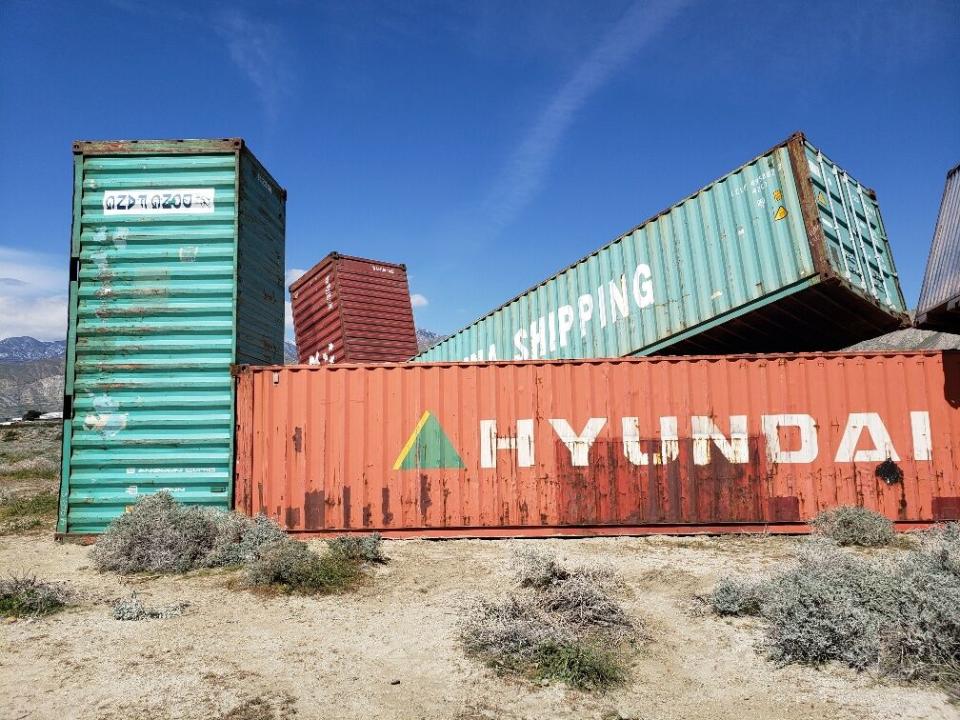 Piled-up freight train cars are part of a sculpture in the desert