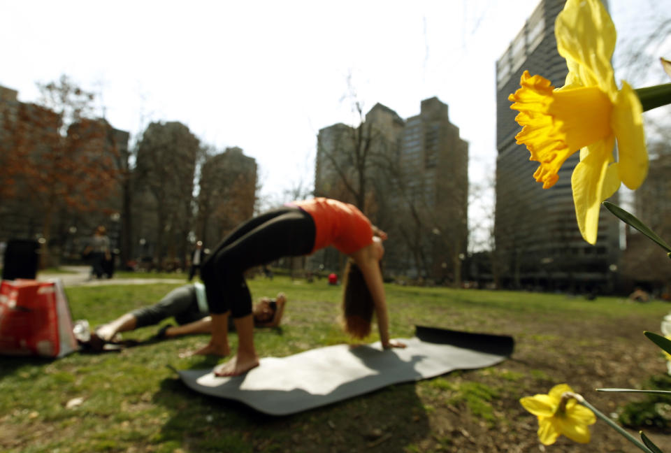 Danielle DelVecchio, left, takes pictures of Aileen Palmer, both of Philadelphia, as Palmer does a yoga pose near the flowers in bloom during the unseasonably warm weather in the Rittenhouse Square park Tuesday, March 13, 2012 in Philadelphia. (AP Photo/Alex Brandon)