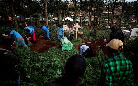 Family members react as they watch a victim of the Ebola virus being buried - Credit: &nbsp;JOHN WESSELS/AFP