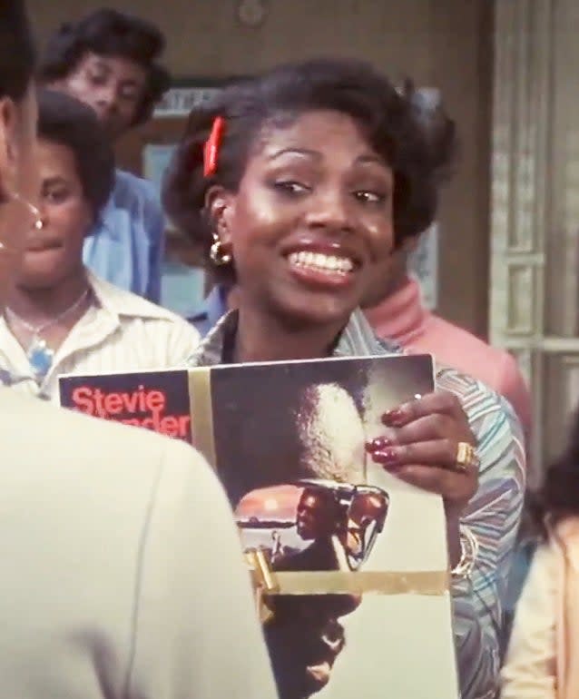 A young Sheryl Lee Ralph holding a Stevie Wonder album with others in the background