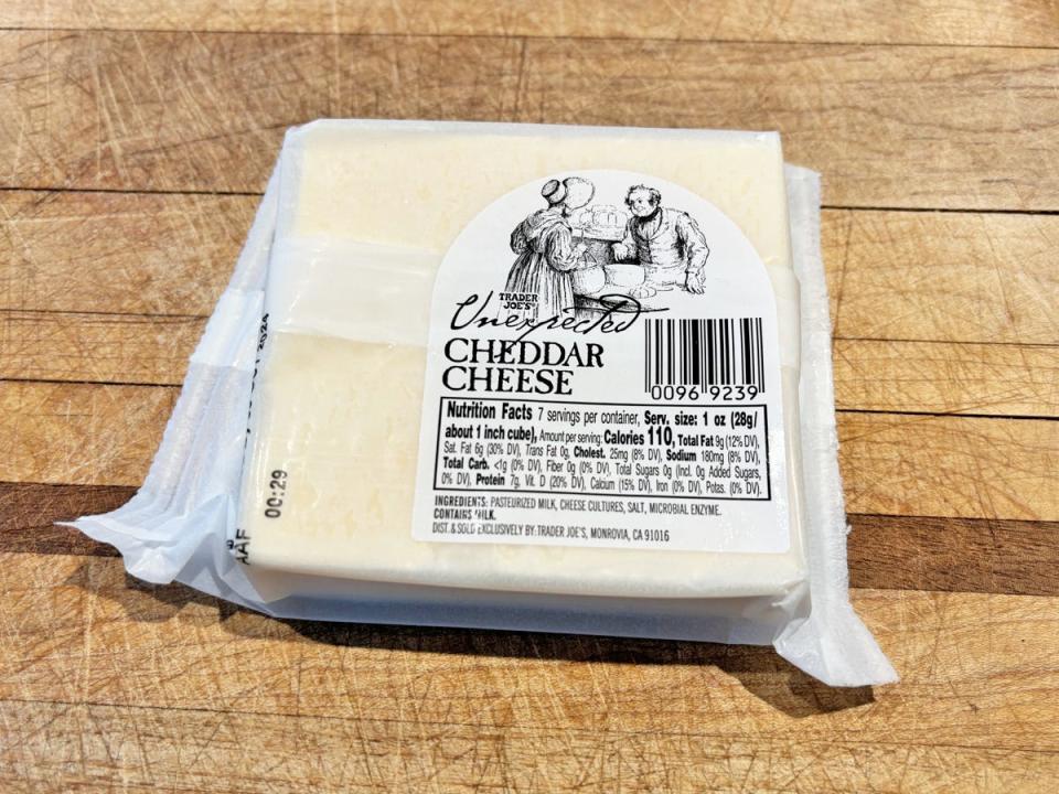 A rectangular block of cheese with a white wrapper depicting an illustration of a woman at a market and a male vendor