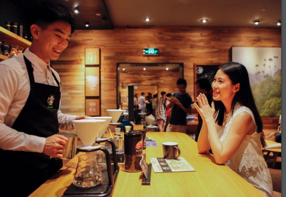Smiling barista preparing coffee for a customer in a Chinese Starbucks.