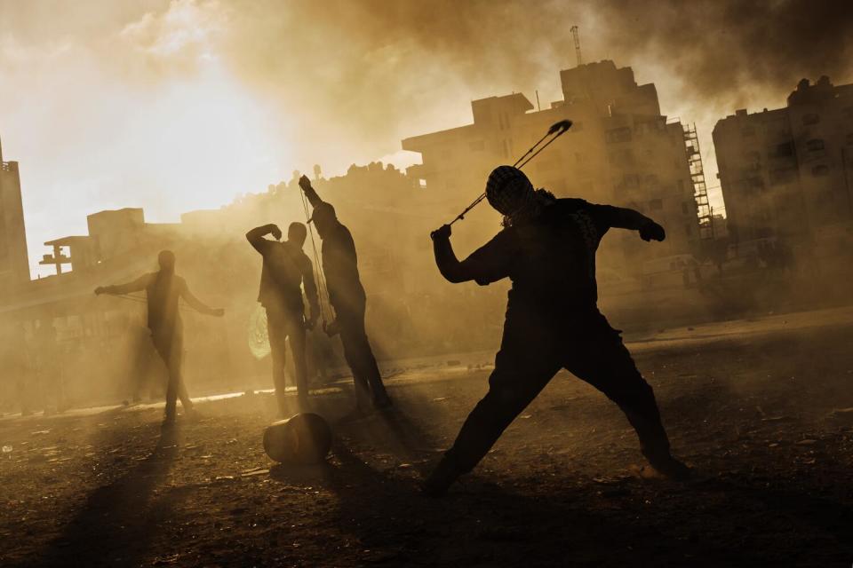 A Palestinian boy slings a rock at Israeli forces as local Palestinians protest Israeli occupation in the West Bank.