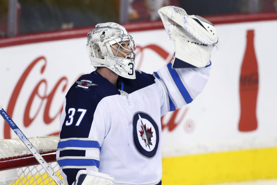 Winnipeg Jets goalie Connor Hellebuyck celebrates after the Jets scored an empty-net goal against the Calgary Flames during the third period of an NHL hockey game Saturday, Nov. 27, 2021, in Calgary, Alberta. (Larry MacDougal/The Canadian Press via AP)