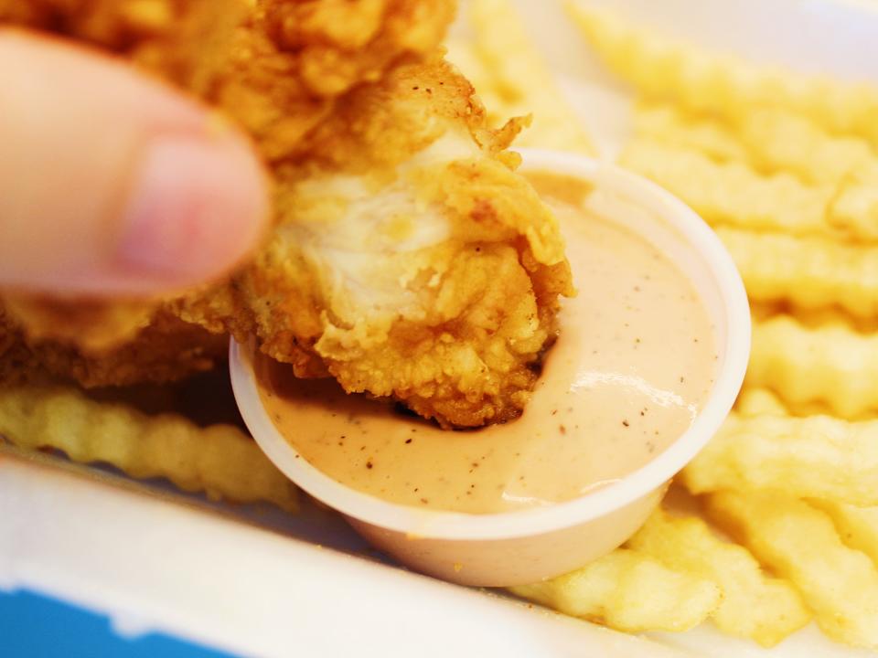 raising canes chicken tender dipped in canes sauce