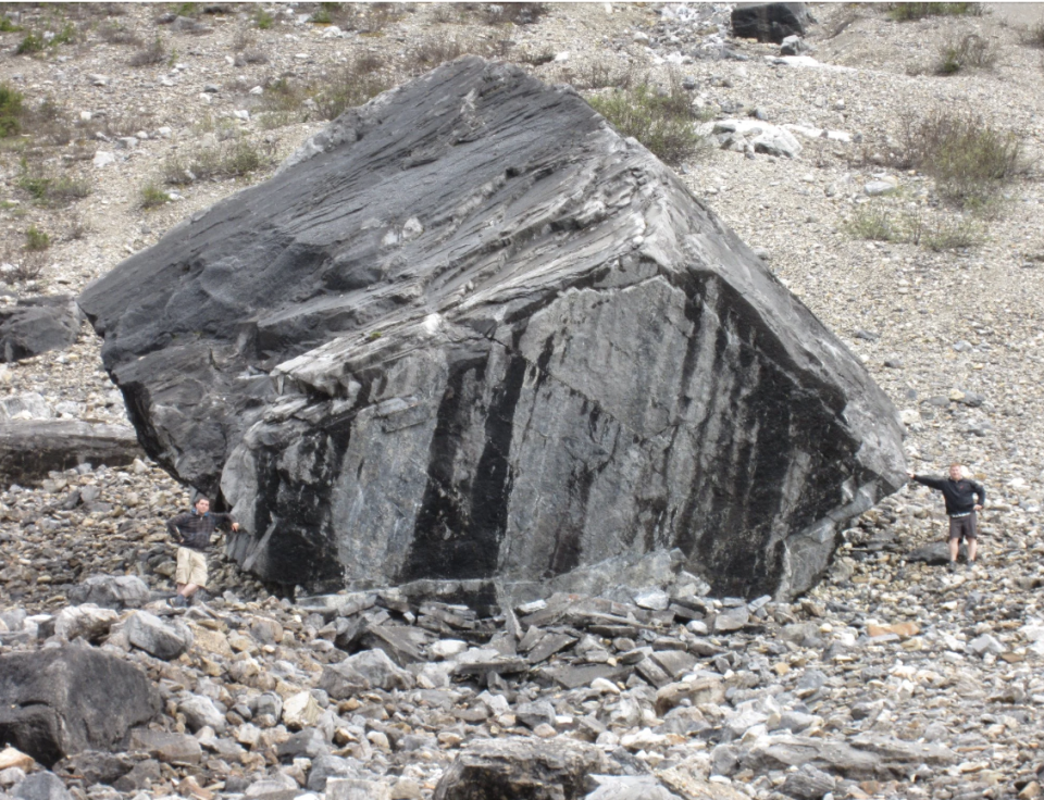 Person beside a large boulder to show scale, located in a rocky terrain