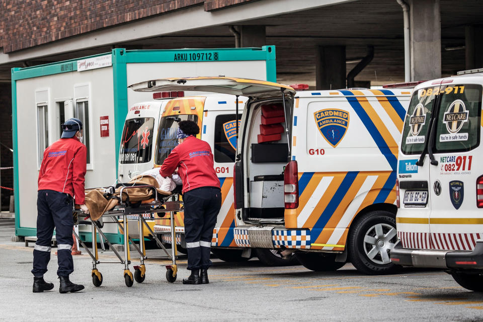 Image: Emergency paramedics wearing full COVID-19 coronavirus personal protective equipment (PPE) carry a patient from an ambulance at the Greenacres Hospital in Port Elizabeth (Marco Longari / AFP - Getty Images)