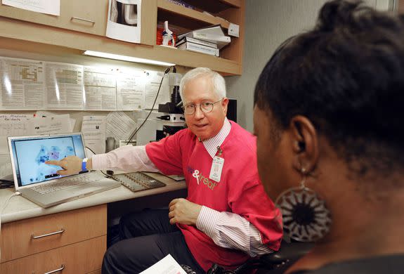 A pathologist from Hennepin County Medical Center in Minneapolis, Minnesota., explains a Pap test slide to a patient at North Point Health & Wellness Center's See, Test & Treat program.
