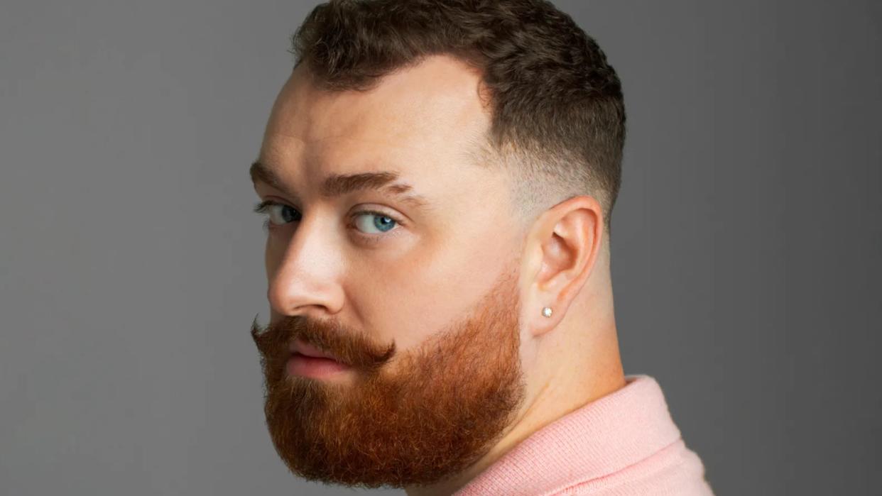 Sam Smith with a beard looking over their shoulder
