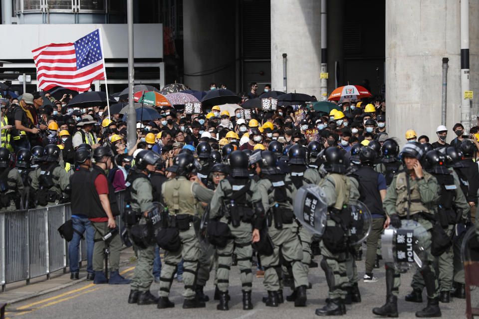 Protesters hoist a U.S. flag as they face off with riot police at the entrance to a village at Yuen Long district in Hong Kong Saturday, July 27, 2019. Thousands of protesters began marching Saturday despite police warnings that their presence would spark confrontations with local residents. Demonstrators wearing black streamed through Yuen Long, the area where a mob brutally attacked people in a commuter rail station last Sunday. (AP Photo/Bobby Yip)