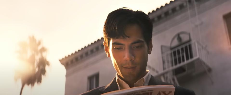 Diego Calva as Manny, looking at Variety magazine outside a mansion