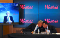Westfield Chairman and co-founder Frank Lowy appears on a screen via video-link as his son Steven Lowy talks with Elliot Rusanow, Chief Financial Officer of Westfield, during a media conference in Sydney, Australia, December 12, 2017. REUTERS/David Gray
