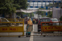 A woman stands on a road blocked by protesters at a demonstration site outside a crematorium where a 9-year-old girl from the lowest rung of India's caste system was, according to her parents and protesters, raped and killed earlier this week, in New Delhi, India, Thursday, Aug. 5, 2021. (AP Photo/Altaf Qadri)