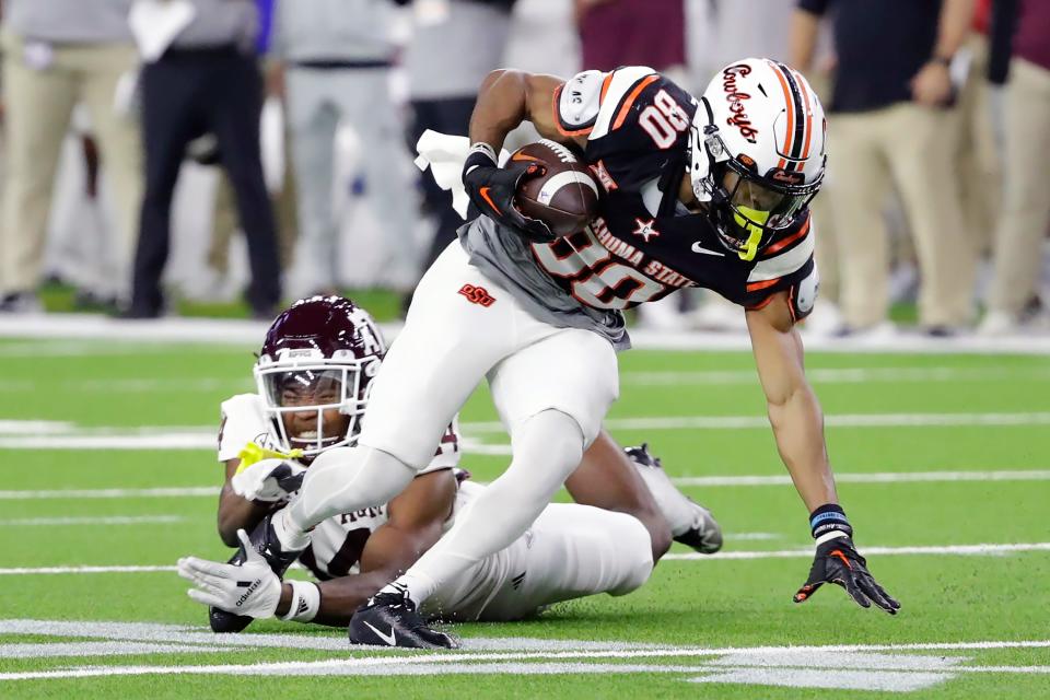 Oklahoma State wide receiver Brennan Presley slips past the tackle attempt by Texas A&M defensive back Jayvon Thomas during the first half of the Texas Bowl NCAA football game Wednesday, Dec. 27, 2023, in Houston. (AP Photo/Michael Wyke)