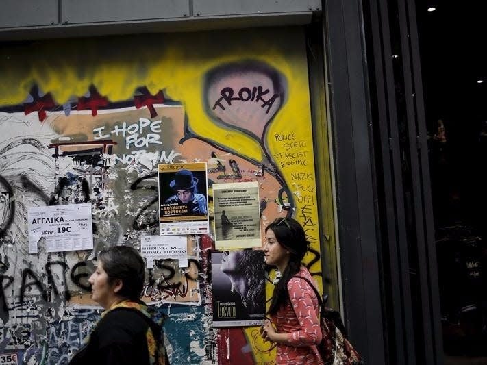 People walk along the commercial Ermou street next to graffiti reading "Troika" in central Athens, Greece, October 20, 2015. REUTERS/Alkis Konstantinidis 