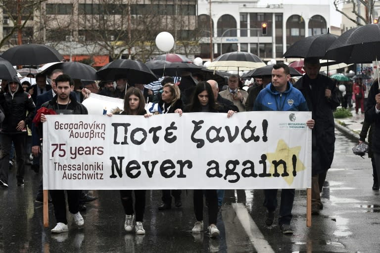 People walk to the old railway station in Thessaloniki bearing banners urging "never again" as they remember the city's deported Jews, 75 years on